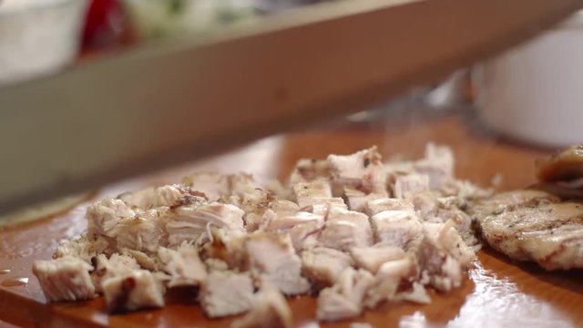 Slow-motion shot of chef assembling chicken street tacos