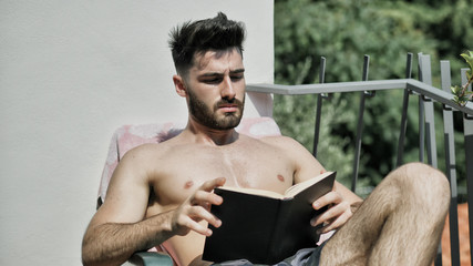 Shirtless Young Man Drying Off in Hot Sun Reading a Book, Muscular Man Wearing Bathing Suit...