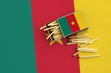 Cameroon flag  is shown on an open matchbox, from which several matches fall and lies on a large...