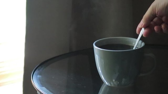 hand stiring a hot cup of coffee