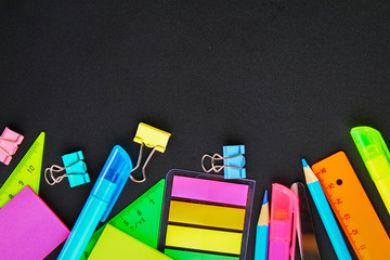 School supplies on blackboard background ready for your design. Flat lay. Top view. Copy space.