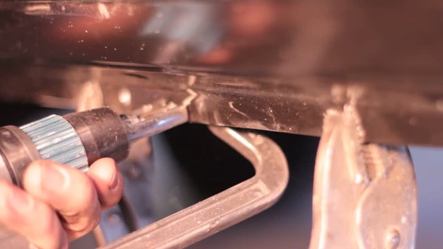 Preparing metal for welding by drilling holes using a spot weld drill. This is part of the automotive repair industry.