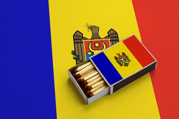 Moldova flag  is shown in an open matchbox, which is filled with matches and lies on a large flag