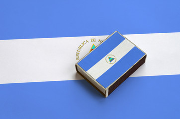 Nicaragua flag  is pictured on a matchbox that lies on a large flag