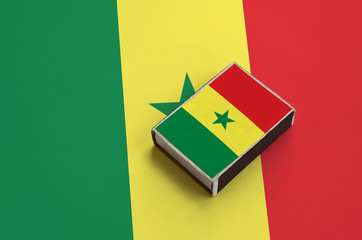 Senegal flag  is pictured on a matchbox that lies on a large flag