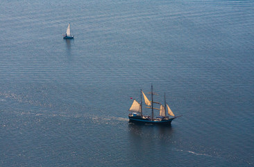 Several yachts and sailboats go to sea under sail. View from above.