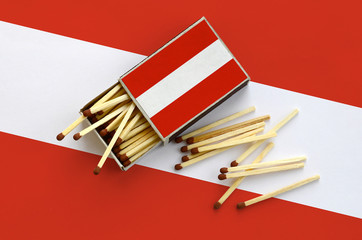 Austria flag  is shown on an open matchbox, from which several matches fall and lies on a large flag