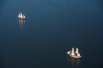 Several yachts and sailboats go to sea under sail. View from above.