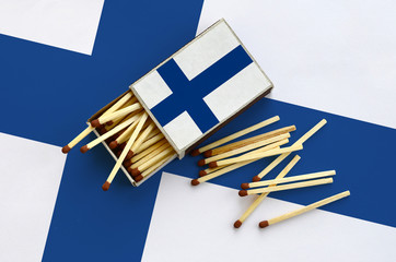 Finland flag  is shown on an open matchbox, from which several matches fall and lies on a large flag