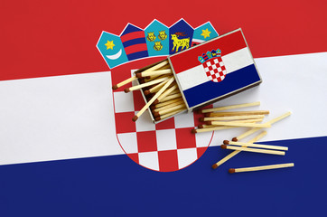 Croatia flag  is shown on an open matchbox, from which several matches fall and lies on a large flag