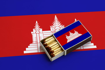 Cambodia flag  is shown in an open matchbox, which is filled with matches and lies on a large flag