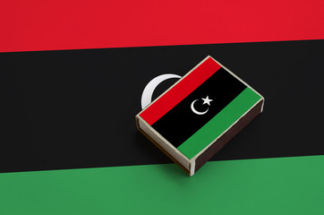 Libya flag  is pictured on a matchbox that lies on a large flag