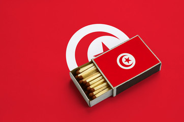 Tunisia flag  is shown in an open matchbox, which is filled with matches and lies on a large flag