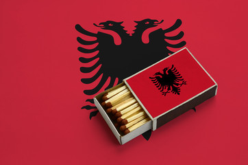  Albania flag  is shown in an open matchbox, which is filled with matches and lies on a large flag