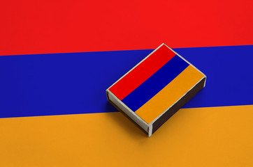 Armenia flag  is pictured on a matchbox that lies on a large flag