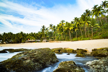 Long exposure. Beautiful and relaxing beach flanked by green palm trees at sunset. Varkala, Kerala, India.