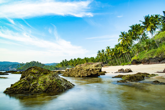 Long exposure. Beautiful and relaxing beach flanked by green palm trees at sunset. Varkala, Kerala, India.