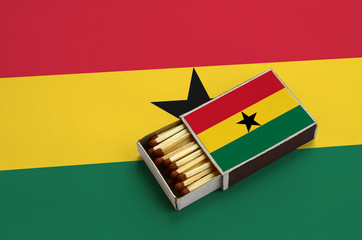 Ghana flag  is shown in an open matchbox, which is filled with matches and lies on a large flag