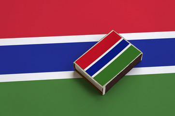 Gambia flag  is pictured on a matchbox that lies on a large flag
