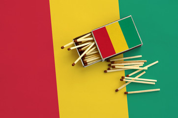 Guinea flag  is shown on an open matchbox, from which several matches fall and lies on a large flag