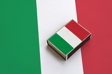 Italy flag  is pictured on a matchbox that lies on a large flag