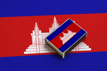 Cambodia flag  is pictured on a matchbox that lies on a large flag