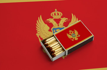 Montenegro flag  is shown in an open matchbox, which is filled with matches and lies on a large flag