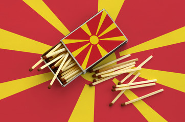 Macedonia flag  is shown on an open matchbox, from which several matches fall and lies on a large...