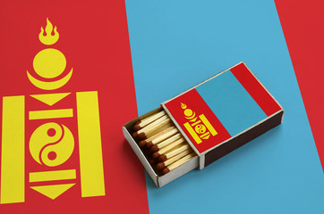 Mongolia flag  is shown in an open matchbox, which is filled with matches and lies on a large flag