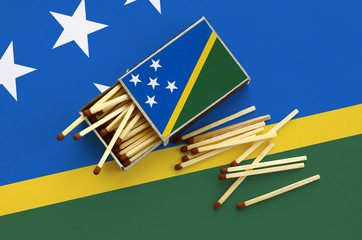 Solomon Islands flag  is shown on an open matchbox, from which several matches fall and lies on a...