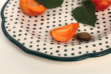 Fruits of apricot on a plate. Apricot ordinary (Latin Prunus armeníaca). On a light background. Selective focus, side view, copy space.
