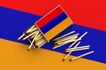 Armenia flag  is shown on an open matchbox, from which several matches fall and lies on a large flag