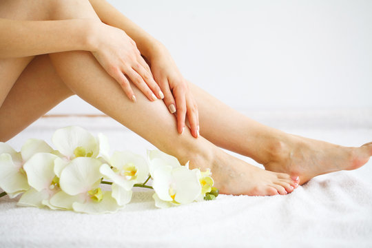 Spa. Woman massaging legs sitting on white background