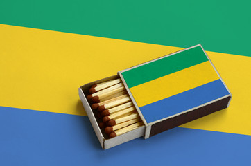 Gabon flag  is shown in an open matchbox, which is filled with matches and lies on a large flag