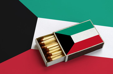 Kuwait flag  is shown in an open matchbox, which is filled with matches and lies on a large flag