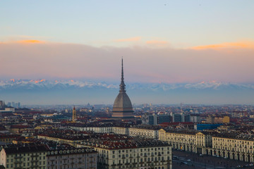 The Mole Antonelliana is seen in the middle. In the background there are the alps during a sunset in Turin, Piedmont, Italy.