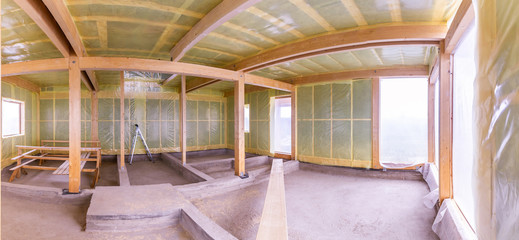 The frame of the house. The frame of the cottage with the warming of the walls. Panorama of the construction site. Walls of a house under construction. Warming of the walls of the building.