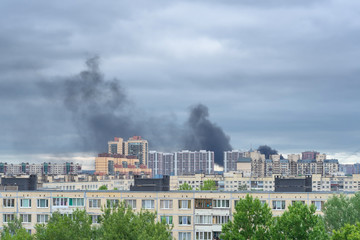 Fire in the city. Black smoke over houses. Fire in a high-rise building.