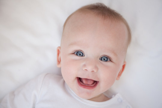 happy smiling child lies on his back on a white sheet