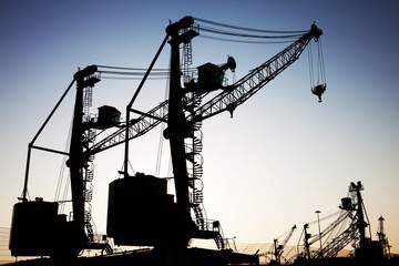 In the evening, the silhouette of port cranes