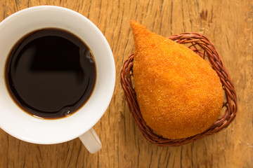 Coxinha is a deep fried food, traditional in Brazil. Snack and espresso coffee on rustic wood, flat...