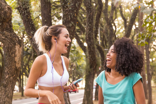 Friends Bonding And Enjoying. They Are Laughing Hard On Wooded Area. Women Are Using Sports Clothing.