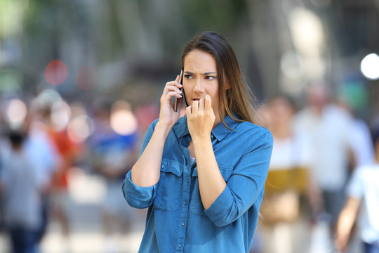 Nervous woman talking on phone on the street