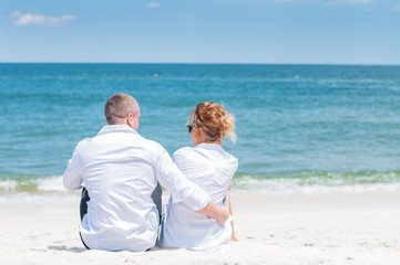 Honeymoon. Happy couple sitting on tropical beach.