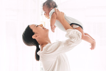 Portrait of happy smiling mother playing with baby on bedroom at home.Love of family concept