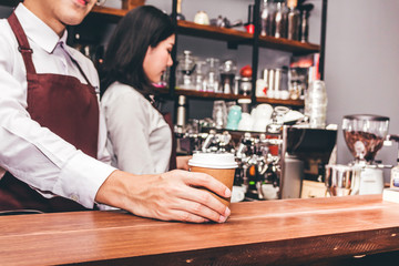 Man barista giving coffee cup to customer at cafe
