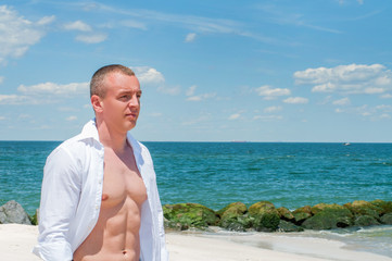 Handsome man is standing on beautiful beach