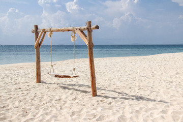 Wooden swing on the sand beach for summer holiday concept.