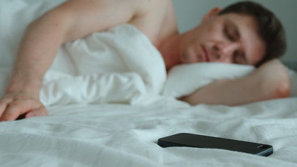 Young adult man sleeps and a phone is near
