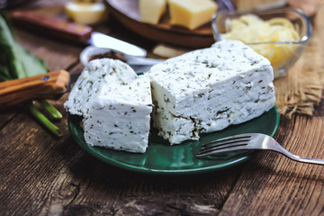 cheese with herbs on a plate. wooden background